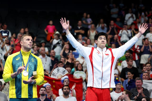 <p>Kyle Chalmers applauds as Pan Zhanle steps on to the Olympic podium</p>