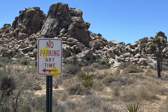 <p>A road sign vandalized with yellow paint in Joshua Tree National Park, California. Three German tourists were cited for firing paintballs throughout the park and could face jail time</p>